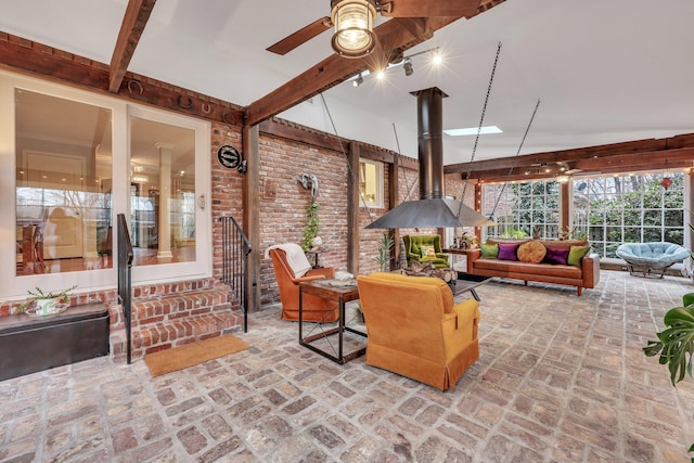 interior space featuring beam ceiling, ceiling fan, and a wood stove