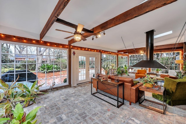 sunroom featuring french doors, ceiling fan, lofted ceiling with beams, and a wood stove