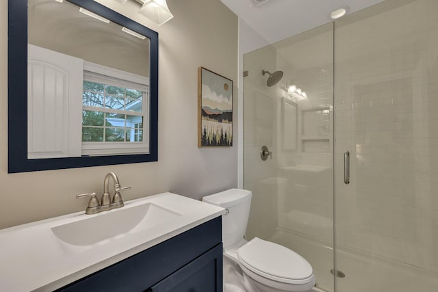 bathroom featuring vanity, a shower with shower door, and toilet