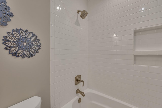 bathroom featuring tiled shower / bath and toilet