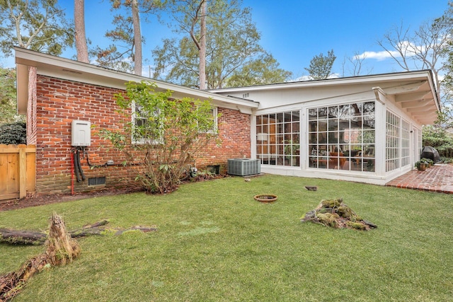 back of property featuring a lawn, a sunroom, and central air condition unit