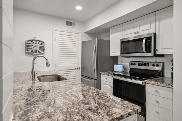 kitchen with light stone countertops, white cabinetry, sink, and stainless steel appliances