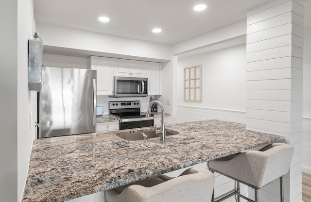 kitchen with white cabinetry, sink, stainless steel appliances, kitchen peninsula, and light wood-type flooring