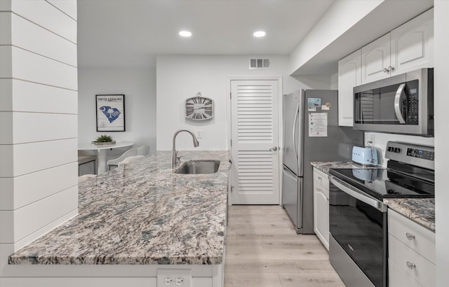 kitchen with sink, light hardwood / wood-style flooring, light stone counters, white cabinetry, and stainless steel appliances