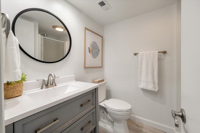 bathroom featuring vanity, wood-type flooring, an enclosed shower, and toilet