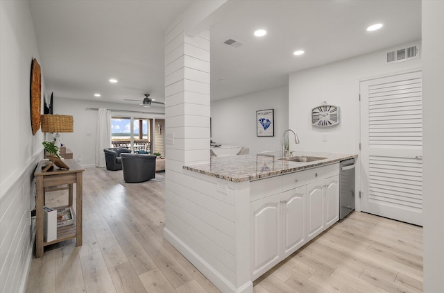 kitchen with white cabinets, sink, stainless steel dishwasher, light stone counters, and kitchen peninsula