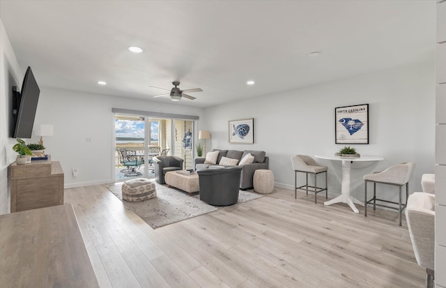 living room with light hardwood / wood-style flooring and ceiling fan