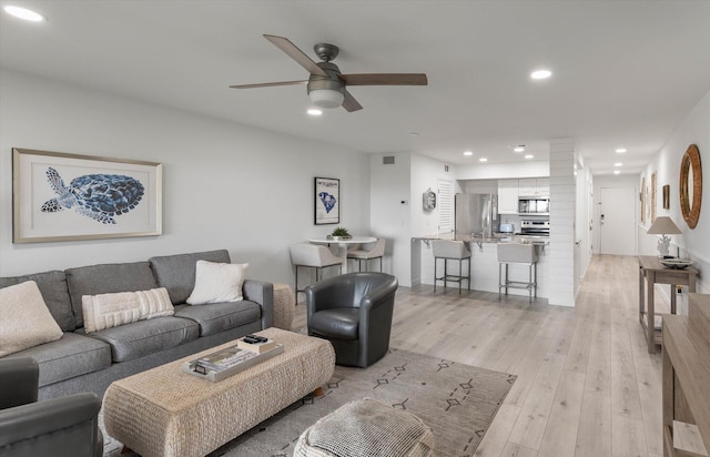 living room with ceiling fan and light wood-type flooring