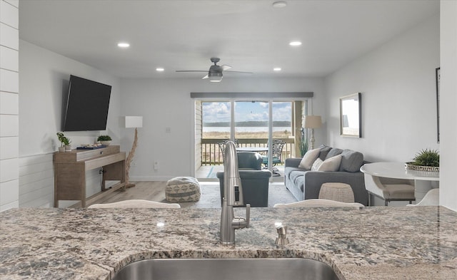 kitchen featuring light stone counters, light hardwood / wood-style flooring, ceiling fan, and sink