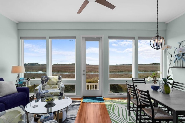 sunroom / solarium featuring a rural view and ceiling fan with notable chandelier