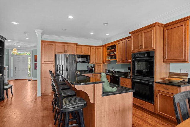 kitchen with light wood-style floors, black appliances, brown cabinetry, and crown molding