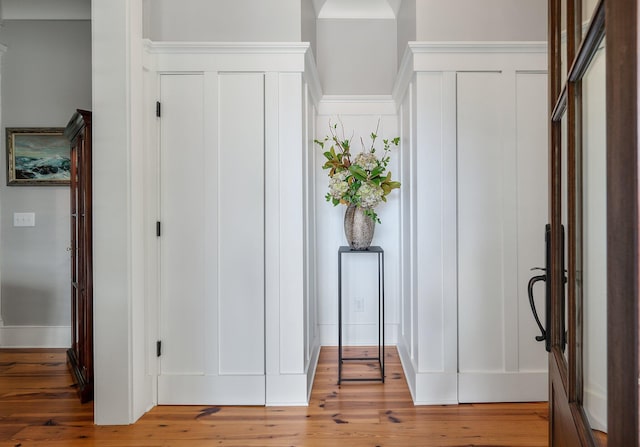 corridor featuring light wood-style flooring and a decorative wall