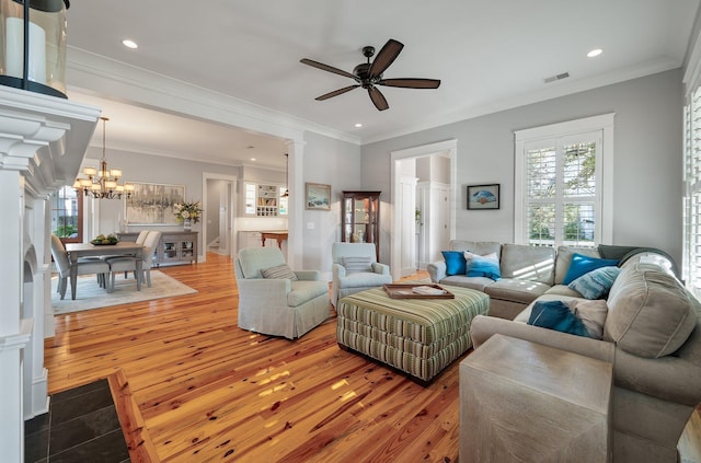 living area featuring light wood-type flooring, ornate columns, visible vents, and ornamental molding