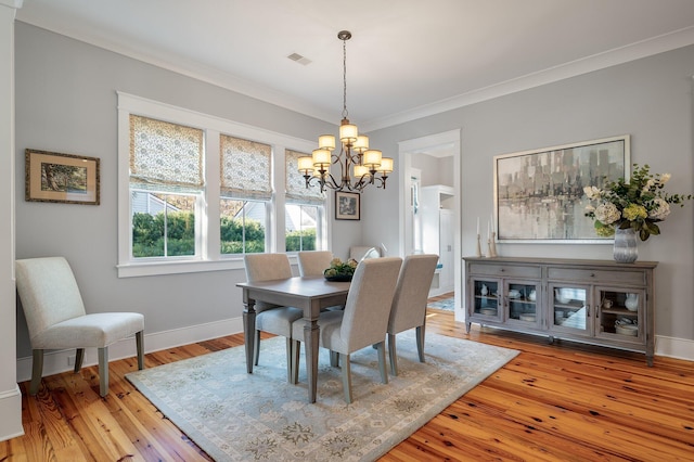 dining space featuring baseboards, visible vents, ornamental molding, an inviting chandelier, and light wood-type flooring