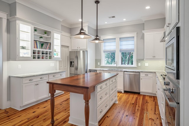 kitchen with stainless steel appliances, a sink, white cabinets, wooden counters, and ornamental molding