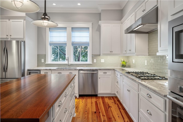 kitchen with under cabinet range hood, butcher block counters, a sink, white cabinets, and appliances with stainless steel finishes