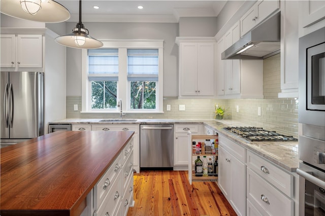 kitchen featuring wood counters, appliances with stainless steel finishes, under cabinet range hood, white cabinetry, and a sink