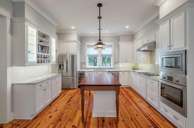 kitchen with appliances with stainless steel finishes, beverage cooler, white cabinetry, and under cabinet range hood