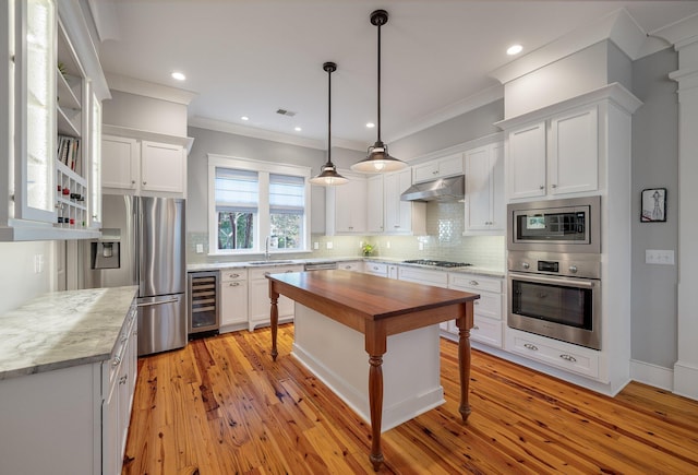 kitchen with under cabinet range hood, beverage cooler, butcher block counters, white cabinets, and appliances with stainless steel finishes