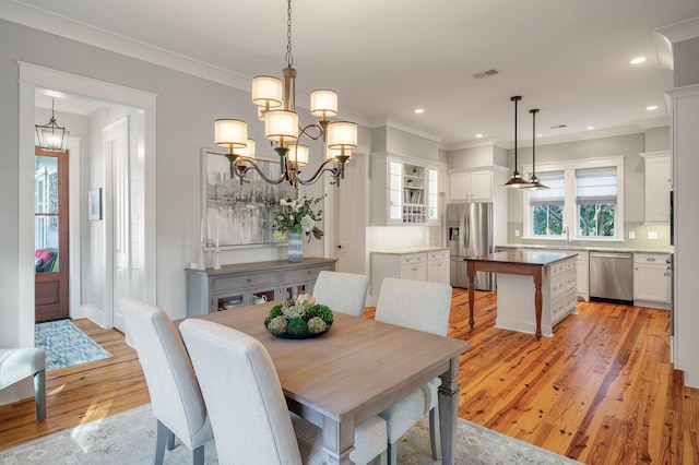 dining room with light wood-style floors, crown molding, a notable chandelier, and recessed lighting