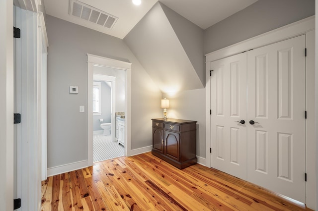 hall featuring light wood finished floors, visible vents, and baseboards