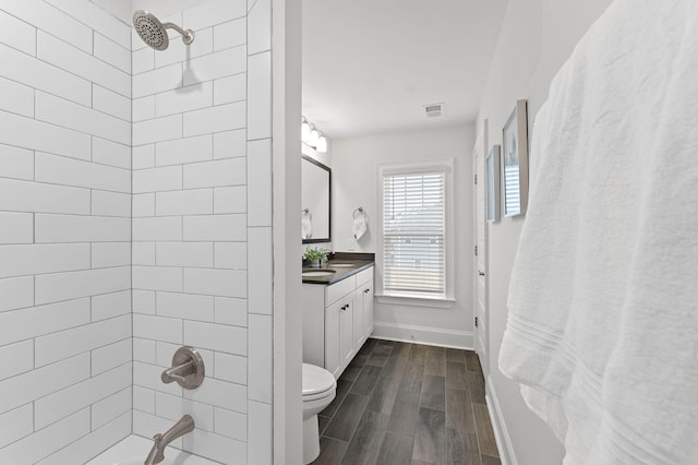 bathroom with wood finish floors, visible vents, toilet, vanity, and  shower combination