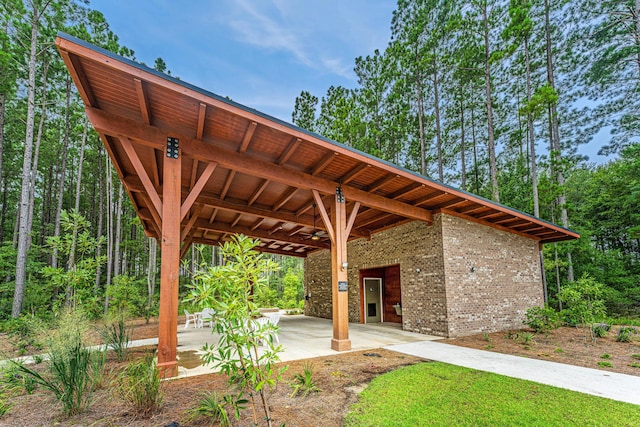 surrounding community featuring driveway, a patio area, a view of trees, and a carport