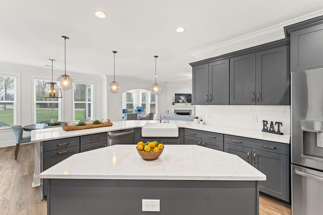 kitchen featuring stainless steel appliances, ornamental molding, a peninsula, and a sink