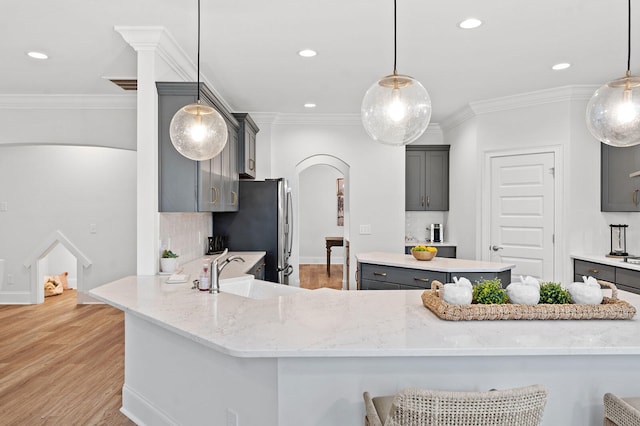 kitchen with arched walkways, gray cabinets, a sink, and freestanding refrigerator