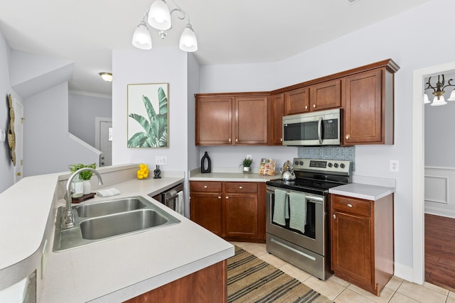 kitchen with light tile patterned flooring, sink, hanging light fixtures, stainless steel appliances, and backsplash