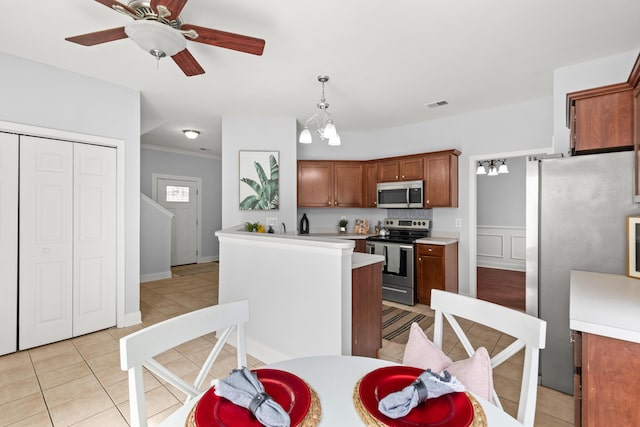 kitchen featuring stainless steel appliances, light tile patterned flooring, ceiling fan with notable chandelier, and pendant lighting