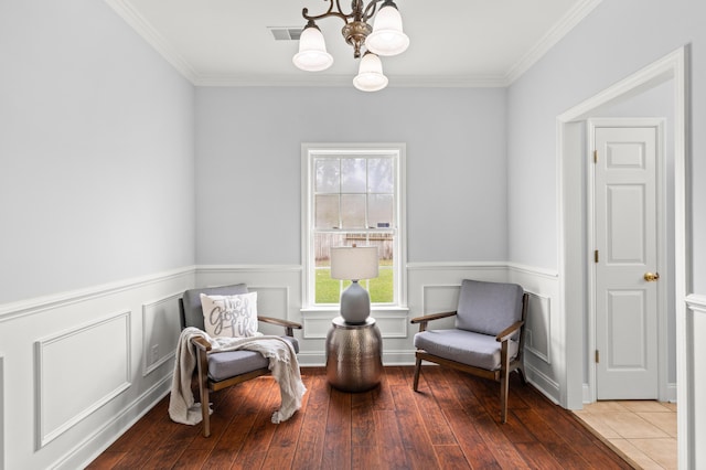 sitting room with crown molding, hardwood / wood-style floors, and an inviting chandelier