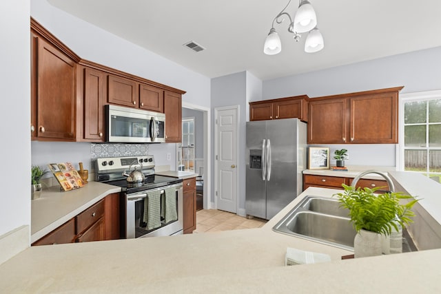 kitchen with appliances with stainless steel finishes, decorative light fixtures, sink, and light tile patterned floors