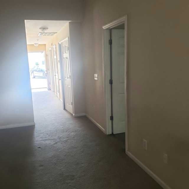 corridor with carpet, visible vents, and baseboards