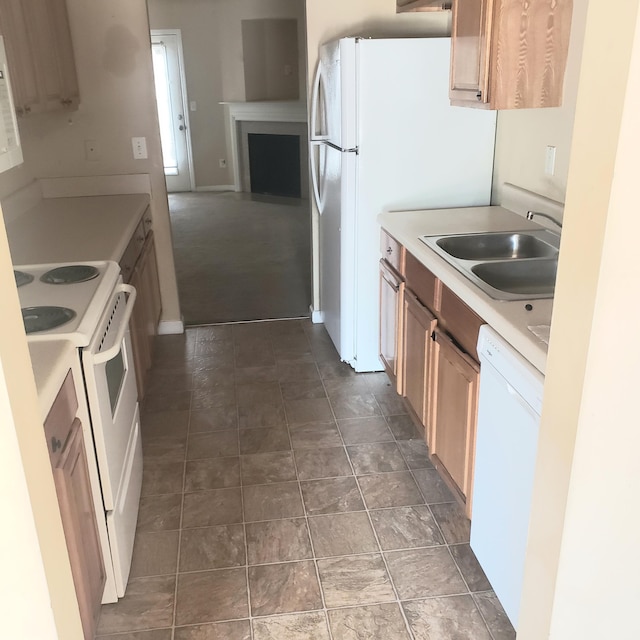 kitchen featuring white appliances, light countertops, a sink, and a fireplace