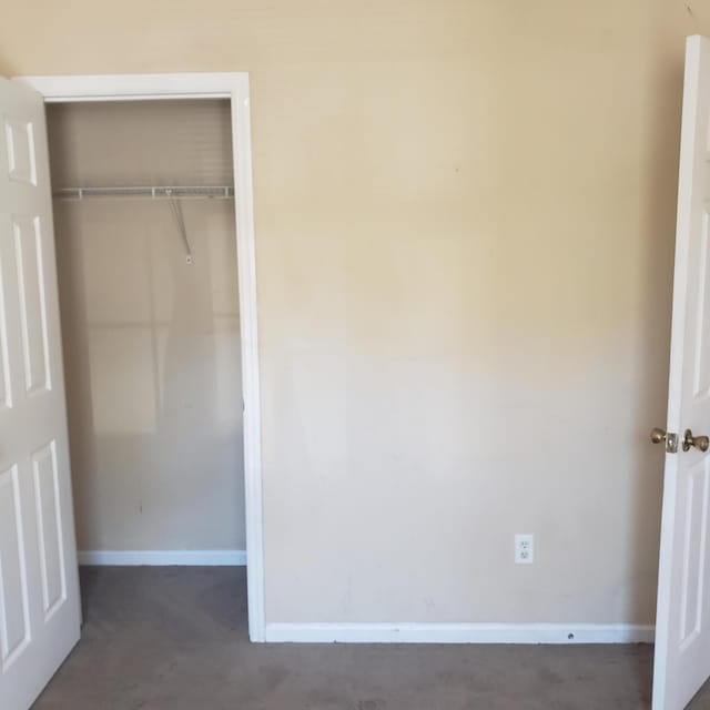 unfurnished bedroom featuring a closet, concrete floors, and baseboards