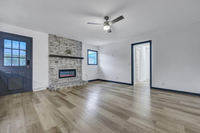 unfurnished living room featuring a ceiling fan, light wood-style flooring, a fireplace, and baseboards