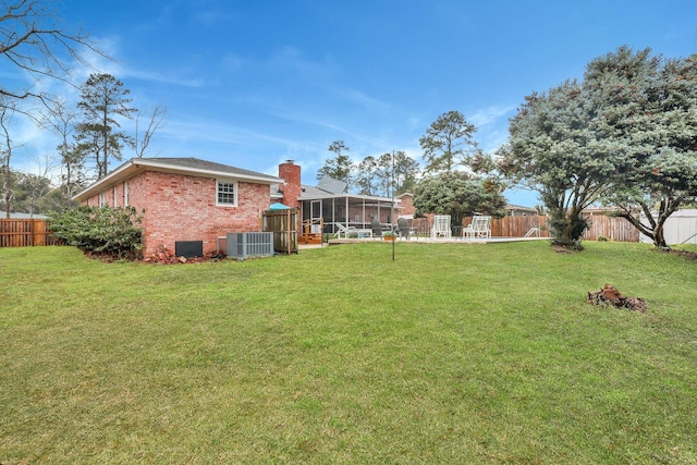 view of yard featuring central air condition unit, a fenced backyard, and a sunroom