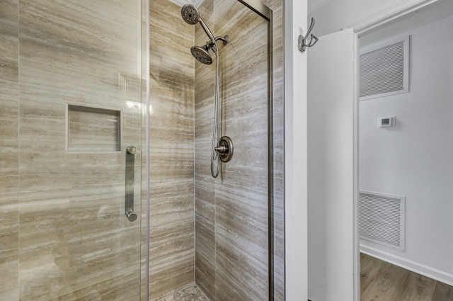 bathroom with a shower stall, wood finished floors, and visible vents