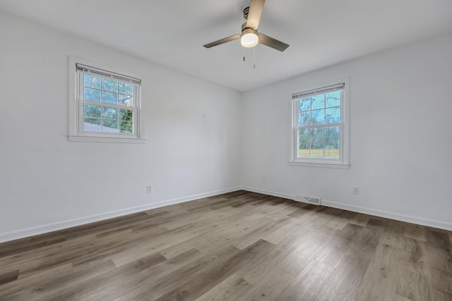 spare room with baseboards, wood finished floors, visible vents, and a healthy amount of sunlight