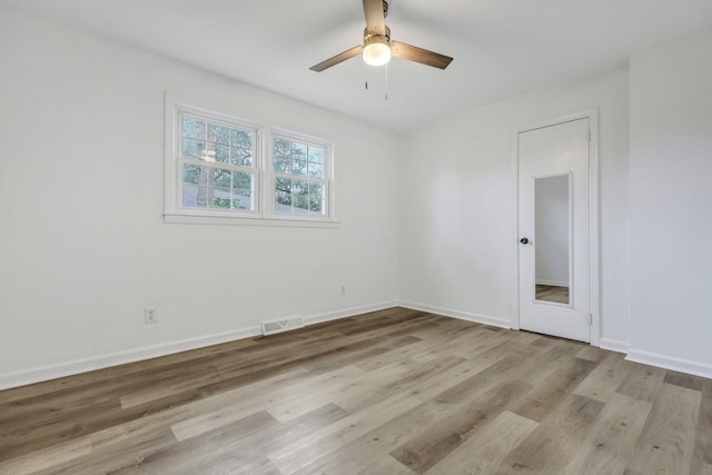 empty room with visible vents, wood finished floors, baseboards, and ceiling fan