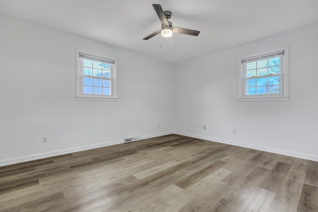 unfurnished room featuring visible vents, baseboards, wood finished floors, and a ceiling fan