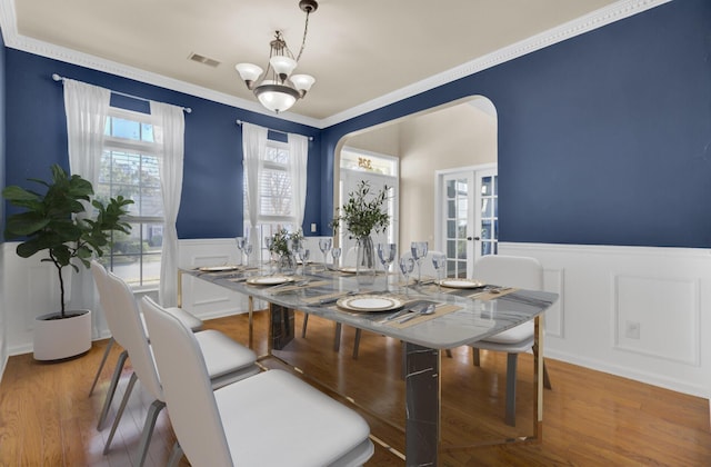 dining area featuring crown molding, french doors, a chandelier, and hardwood / wood-style flooring