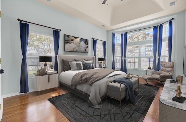 bedroom with hardwood / wood-style floors, ceiling fan, and a towering ceiling