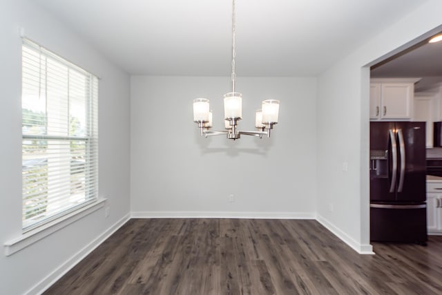 unfurnished dining area featuring a chandelier, a wealth of natural light, and dark wood-style floors