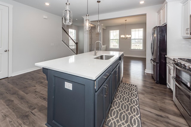 kitchen with white cabinets, stainless steel appliances, an inviting chandelier, light countertops, and a sink