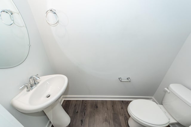 bathroom with toilet, wood finished floors, and baseboards