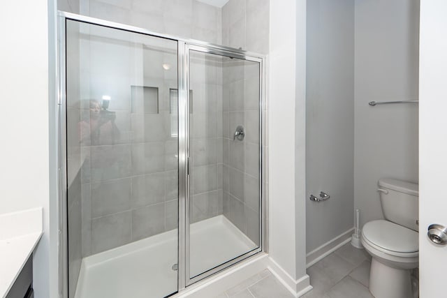 full bath featuring a shower stall, tile patterned flooring, baseboards, and toilet