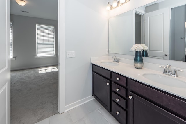 full bath featuring baseboards, visible vents, a sink, and double vanity