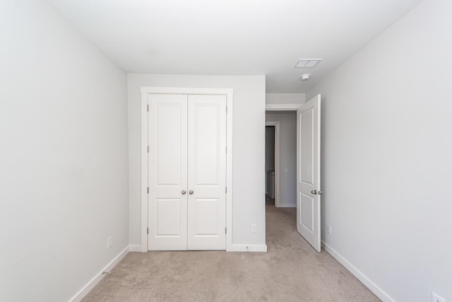 unfurnished bedroom featuring baseboards, a closet, light colored carpet, and visible vents